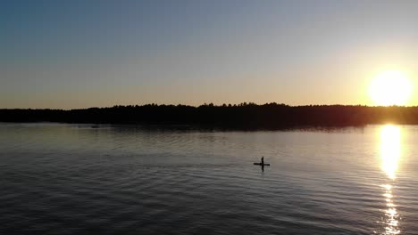 paddleboarding in the sunset at a swedish lake during a warm summer night