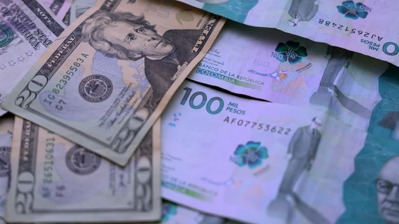 Detailed view of Colombian pesos and US dollars scattered on a surface, showcasing international currency exchange. Soft lighting highlights the textures and colors of the notes