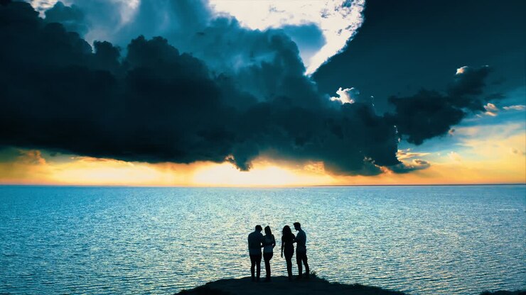 The four people standing on the mountain top against the picturesque seascape