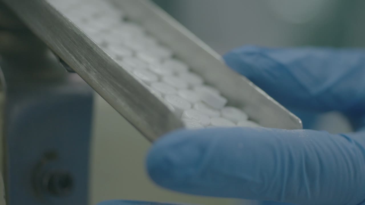 close-up view of a researcher covering the tablet exit with their hand and then releasing it, controlling the flow of tablets.