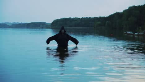 evil witch in black cloak with hood in the river. halloween costume.