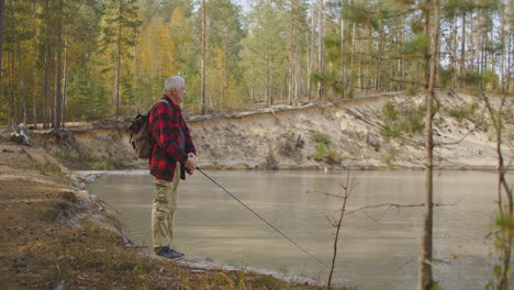 Fischer-Mit-Rute-Angelt-Spinnfischen-Allein-An-Der-Küste-Eines-Ruhigen-Flusses-Und-Entspannt-Sich-Bei-Schönem-Wetter-Am-Herbsttag-In-Der-Natur