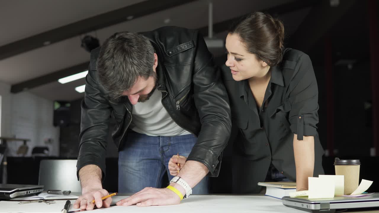 hombre y mujer jóvenes trabajando en un proyecto, dibujando y pensando en una oficina moderna. usando brújula. filmado en 4k.