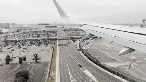 Blick-Auf-Den-Flügel-Eines-Flugzeugs,-Das-Auf-Einer-Geschäftigen-Stadt-Voller-Gebäude-Landet