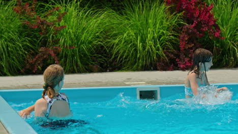 dos chicas divirtiéndose salpicando en una piscina