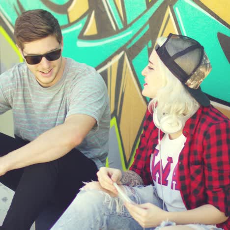 Hipster-couple-relaxing-against-a-graffiti-wall