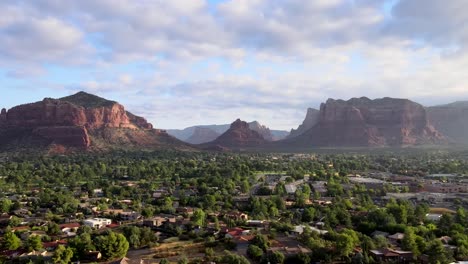 descending aerial over neighborhood of houses, bells rock and courthouse butts, cloudy sedona arizona