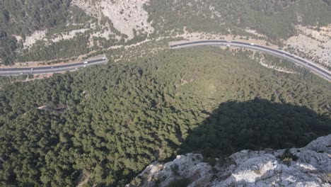 Tráfico-Por-Carretera-Que-Pasa-Por-Las-Montañas,-Vista-Del-Túnel-Tomada-Desde-El-Acantilado-Con-Un-Drone