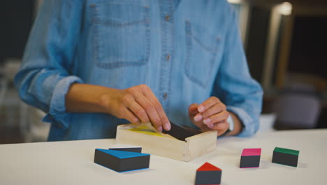 young businesswoman in modern office doing shape puzzle on table