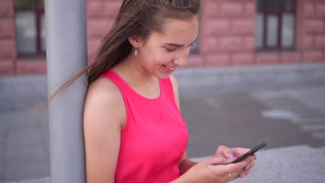 joven bonita usando un teléfono inteligente mientras está sentada al aire libre
