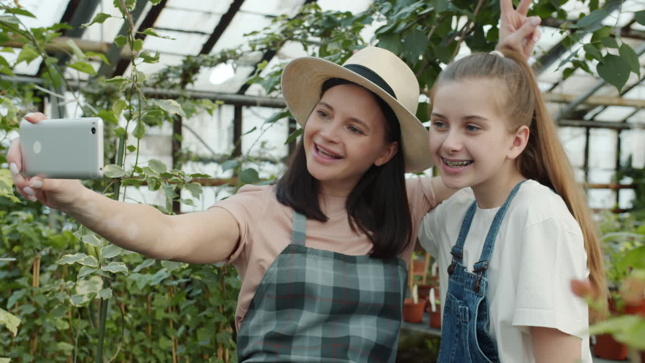 Mother and Daughter Taking a Selfie in a Greenhouse