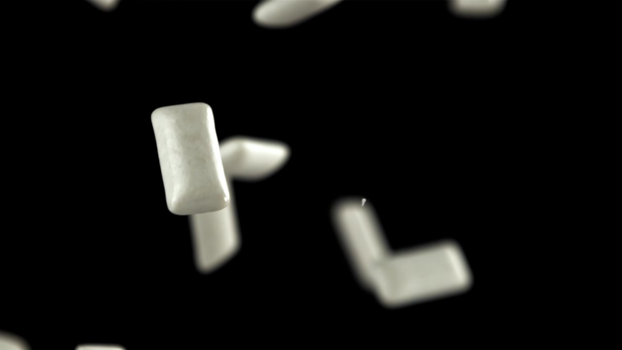 White Chewing Gum Pieces Falling and Floating on Black Background