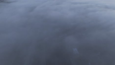 Flying-over-the-low-clouds-at-Dinant-Belgium-during-sunrise,-aerial