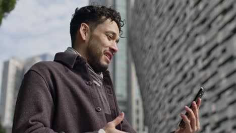 Caucasian-modern-well-dressed-male-in-video-call-holding-modern-smartphone-happily-talk-outdoor-in-sunny-day,-close-up-slow-motion