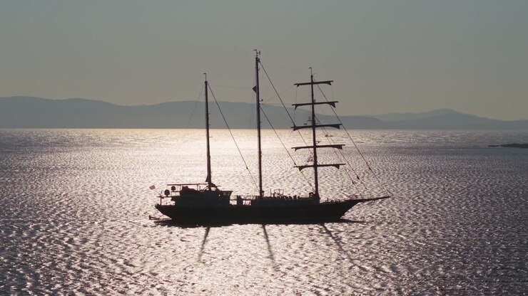 Un maestoso veliero a tre alberi riflette la luce del sole sulla superficie scintillante del Mar Egeo.