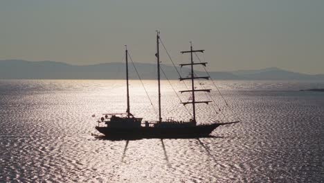 a majestic sailing ship with three masts reflects sunlight on the shimmering aegean sea surface