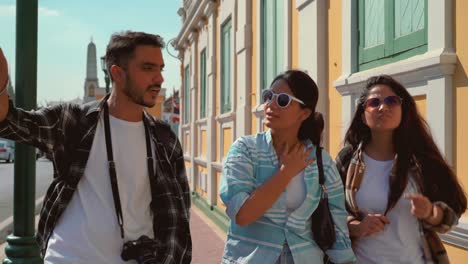 happy group of tourist backpacker friends traveling while talking and walking pedestrian street attraction in bangkok, thailand, group of happy young male and female are enjoying sightseeing