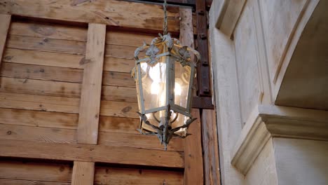 slow orbiting shot of a historic metal and glass lantern hanging within a castle