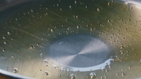 close-up of olive oil being poured into heated steel pan for cooking