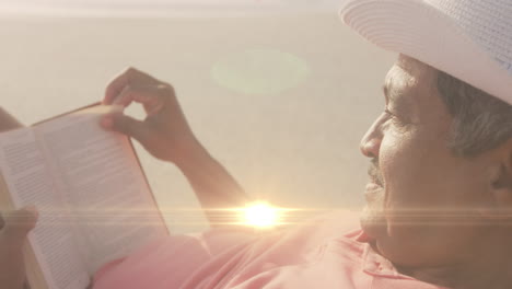 Animación-De-Puntos-De-Luz-Sobre-Un-Hombre-Birracial-Leyendo-En-La-Playa.