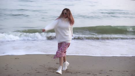 a stylish woman whirling happily on the autumn seashore spreading hands