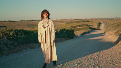 relaxed girl walking pathway in sunlight vertical. smiling woman enjoying nature