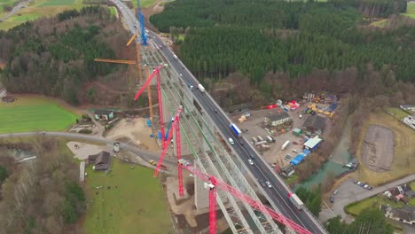 Luftaufnahme-Von-Lastwagen-Und-Autos,-Die-über-Die-Brücke-Neben-Der-Im-Bau-Befindlichen-Neuen-Brücke-Fahren