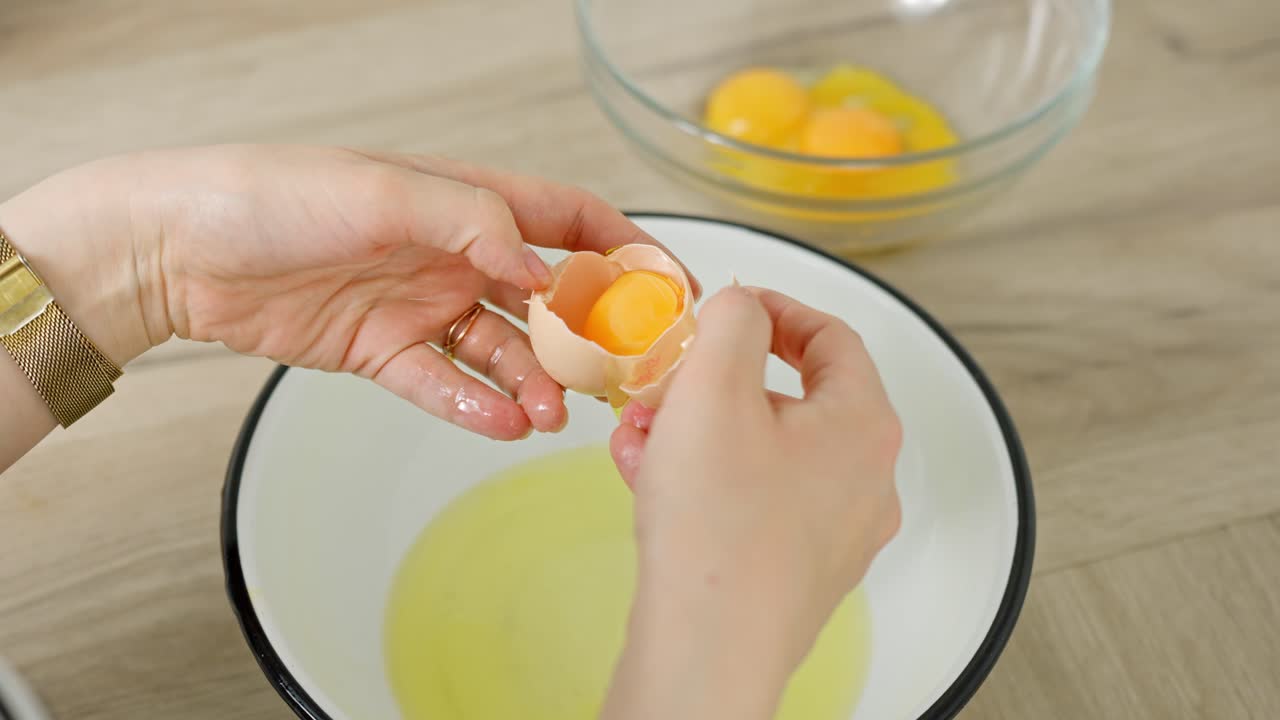 Separating an egg yolk from the white to make a tiramisu dessert