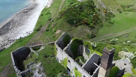 Abandoned-overgrown-ivy-covered-desolate-countryside-historical-Welsh-coastal-brick-factory-mill-aerial-top-down-flyover-view