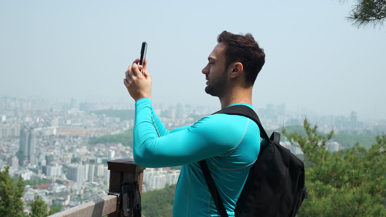 Male blogger tourist traveler takes pictures of beautiful Seoul city landscape overlooking from top of Gwanaksan mountain , South Korea