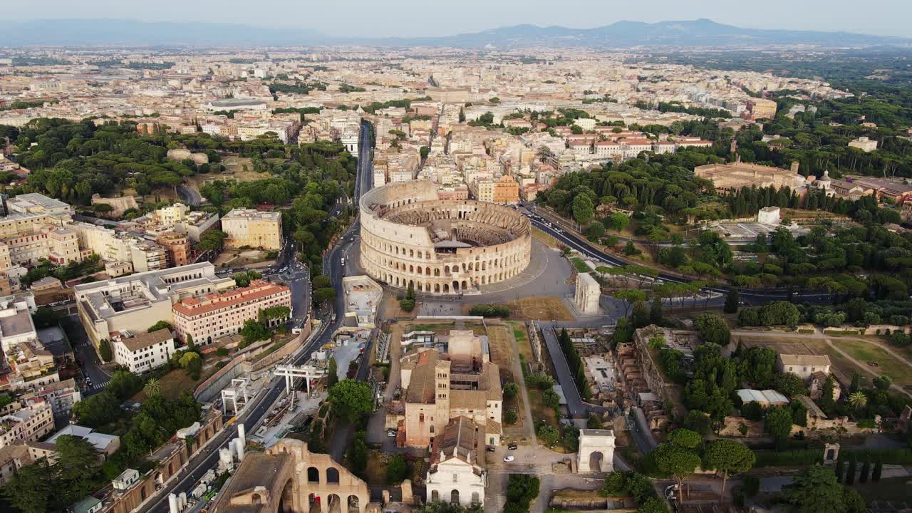 Colosseum stands illuminated at sunset, surrounded by Rome vast skyline, static