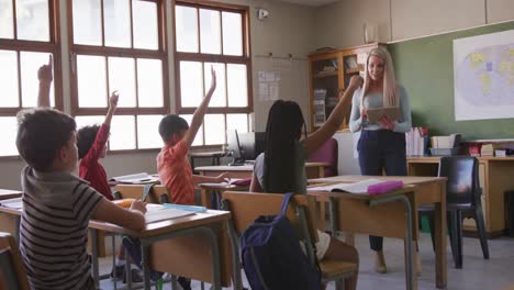 Grupo-De-Niños-Levantando-La-Mano-En-La-Clase-En-La-Escuela