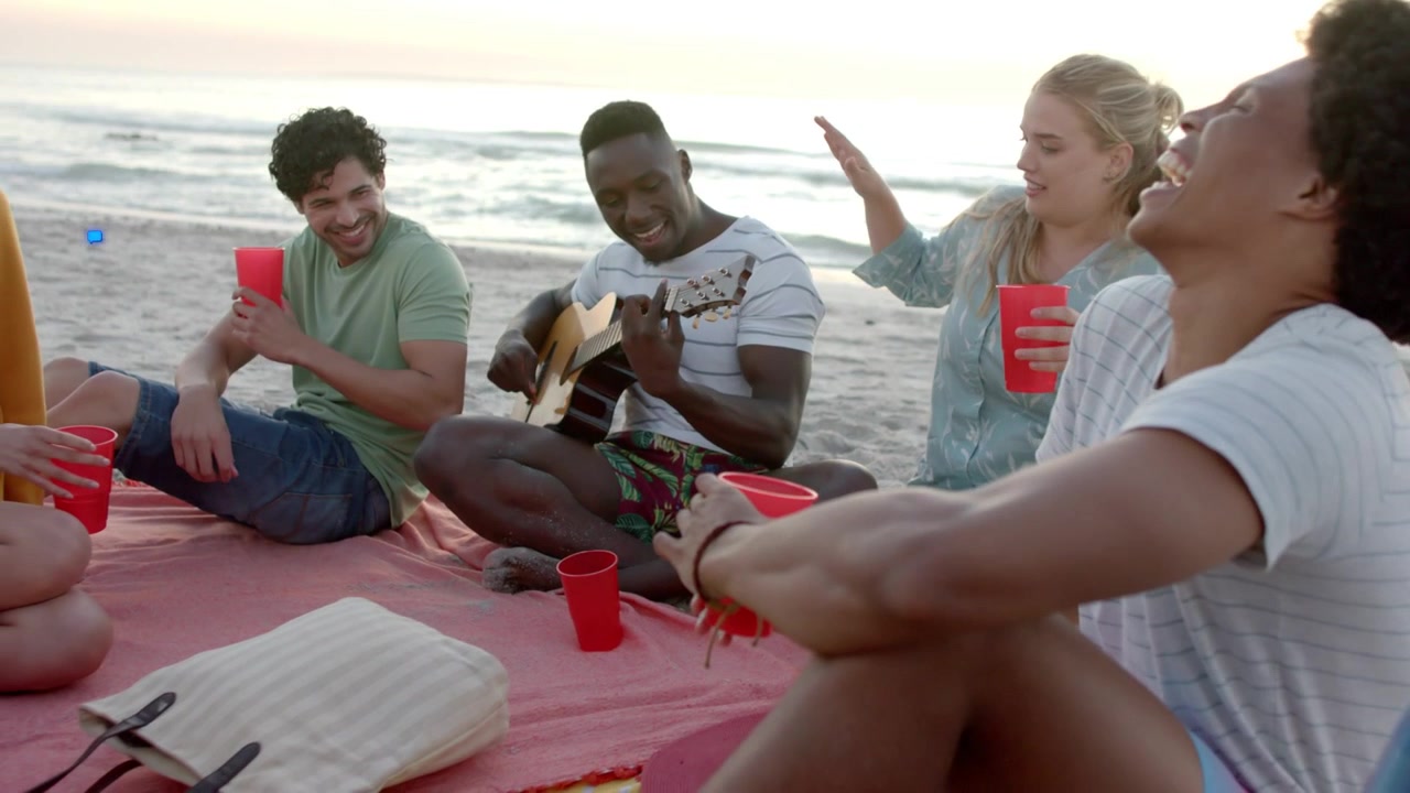 Guitarist playing on beach mat, friends laughing at sunset, social icons rising showing engagement