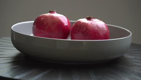 adding two pomegranates in bowl creating a pomegranate cocktail concoction juicing and using fresh ingredients and pomegranate seeds