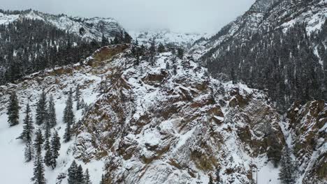 Drone-aerial-view-of-snow-capped-rocky-hills-in-cold-mountain-winter-landscape