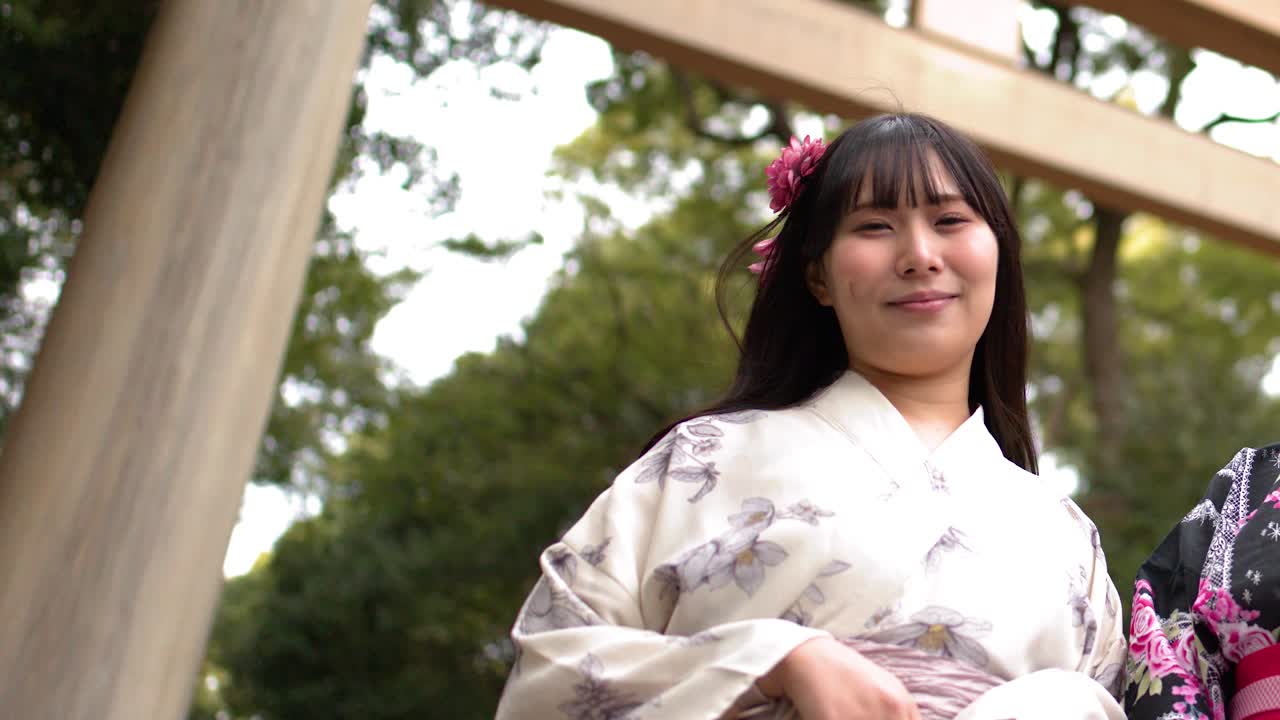 Plano contrapicado de una mujer japonesa sonriente vistiendo un kimono en un santuario sintoísta.