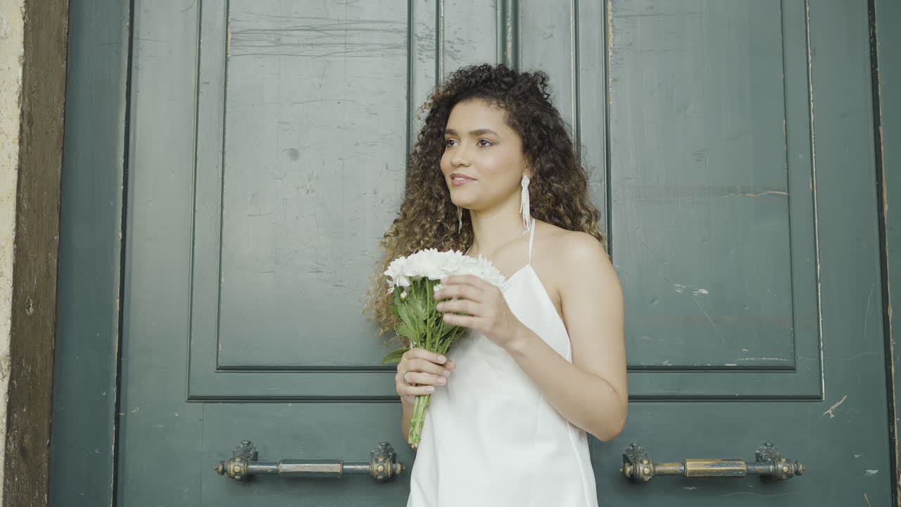Mujer con flores frente a una puerta