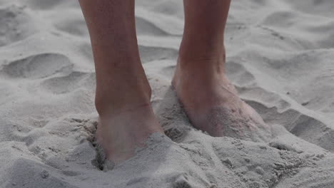 A-woman-hides-her-feet-in-the-sand-on-the-beach-to-hide-athlete's-foot