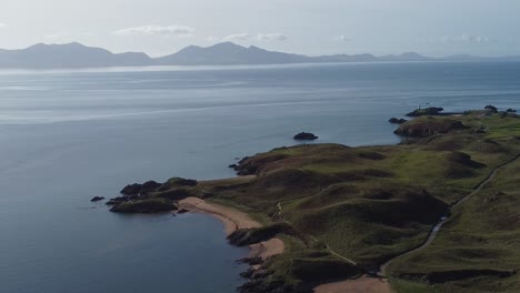 vista aérea que desciende a la isla de ynys llanddwyn con la nebulosa cordillera de snowdonia a través del mar de irlanda al amanecer