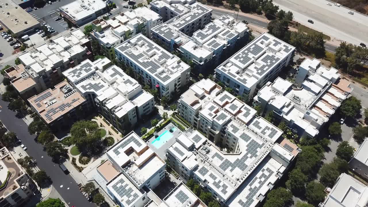 Ripresa aerea dall'alto di moderni condomini residenziali di lusso a Pasadena, California, con tetti dotati di pannelli solari, piscina centrale e abitazioni urbane organizzate, in pieno giorno. Quartiere suburbano.