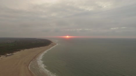 Aerial:-Sunset-at-the-beach-with-the-sun-lighting-up-above-the-horizon