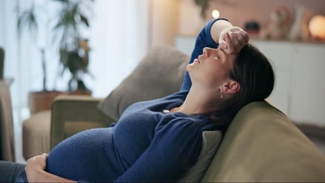 pregnant woman with headache lying on couch