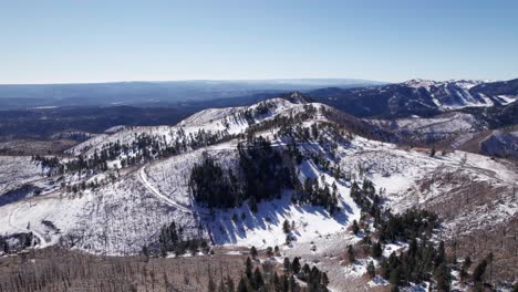 Drone-shot-looking-down-on-a-winding-mountain-road-in-the-winter