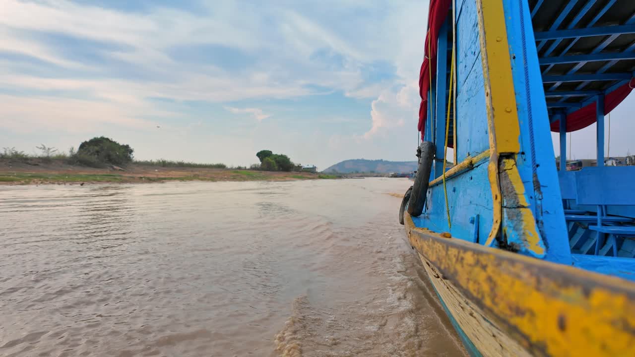 View from a colourful traditional cambodian boat, capturing a calm stretch of the Mekong River.