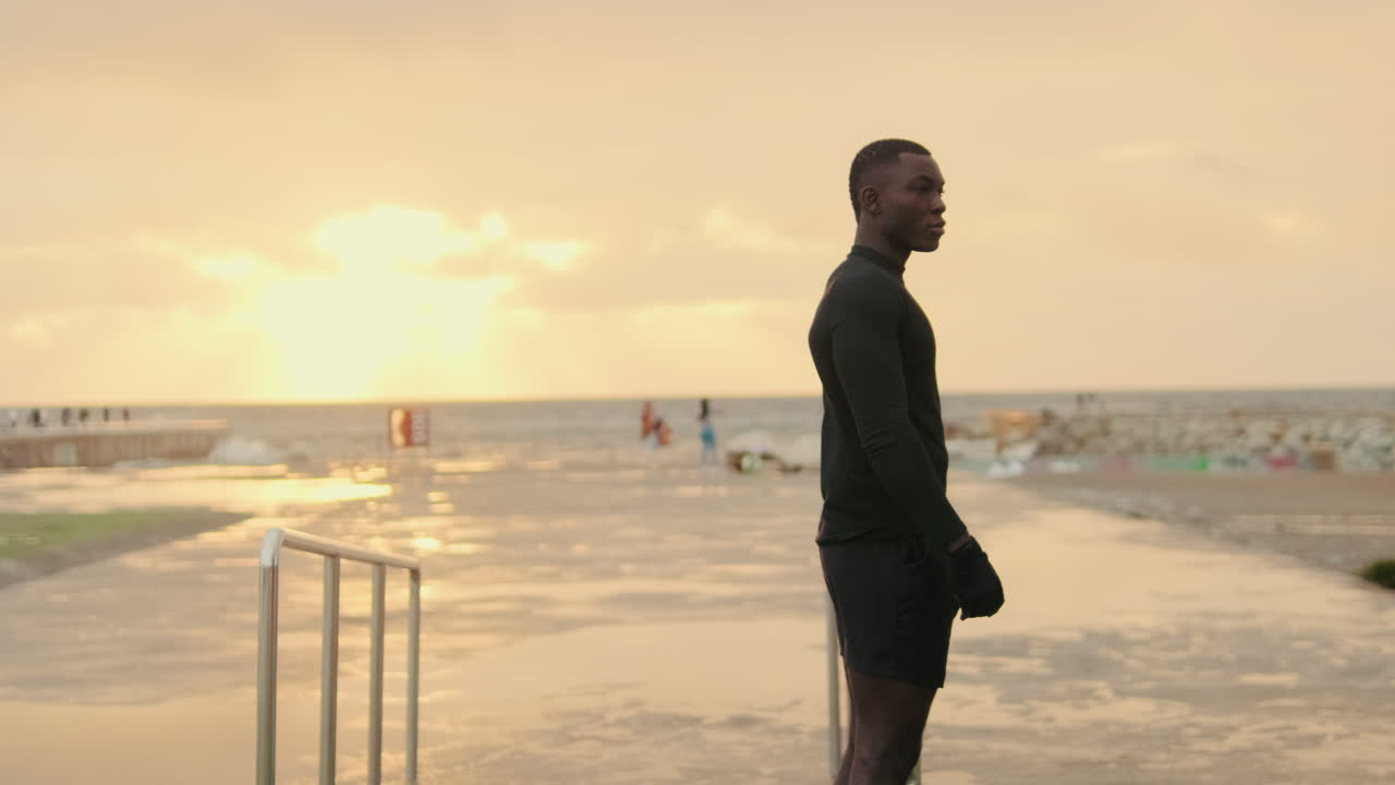 Jovem Pugilista em pé à beira-mar ao pôr do sol dourado