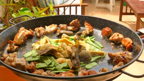 cocinando una gran sartén de paella con pollo y verduras - de cerca