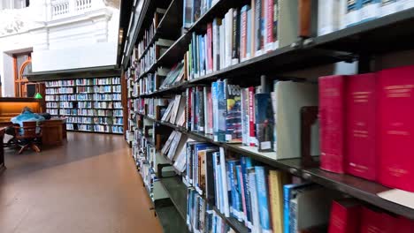 person walking past bookshelves in library