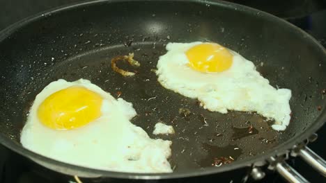 dos huevos con el lado soleado hacia arriba chisporrotean, al vapor en una sartén caliente no pegajosa