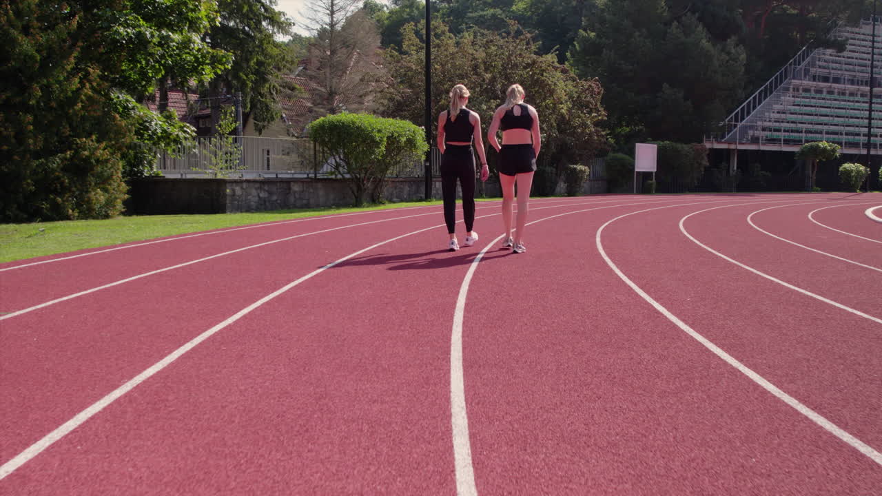Two Female Athletes Walking on a Running Track