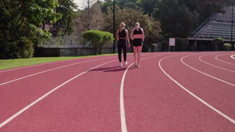 two female athletes walking on a running track